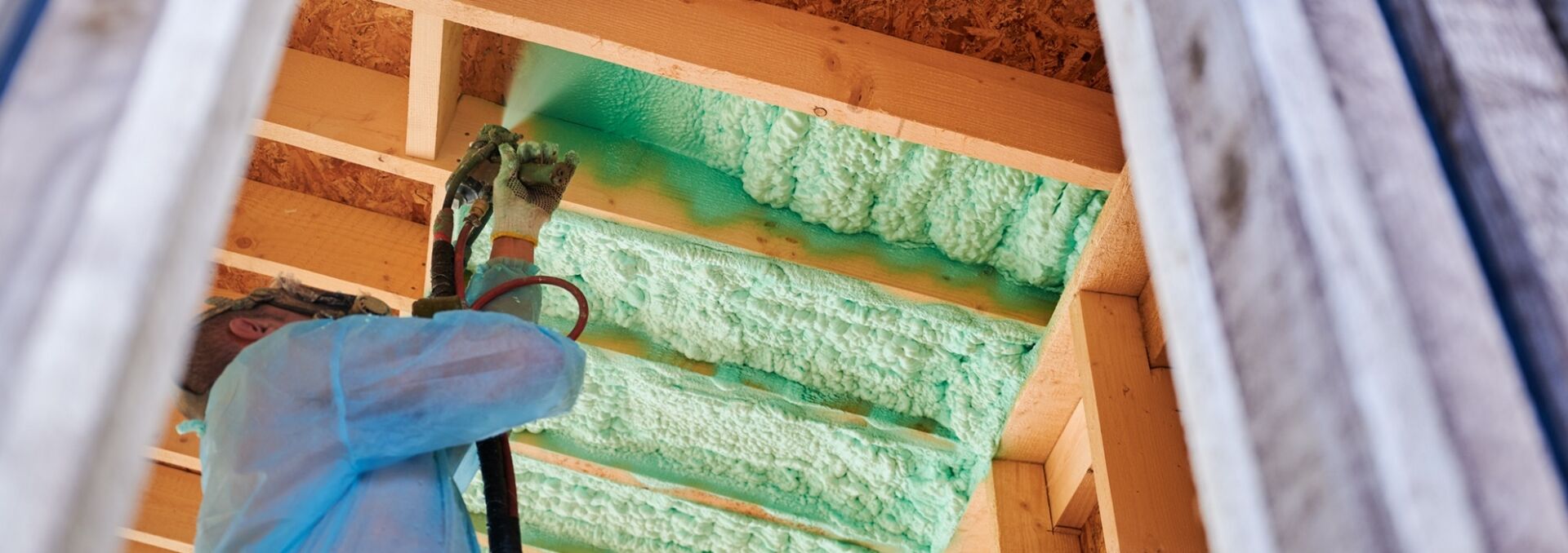 Worker Spraying Polyurethane Foam For Insulating Wooden Frame House. Worker Spraying Polyurethane Foam For Insulating Wooden Frame House.